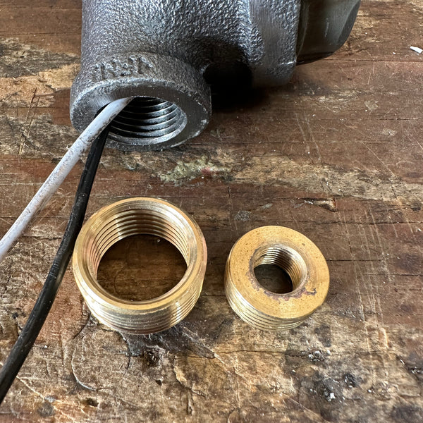 Brass threaded fittings and wiring components for Steampunk Pipe Lamp Dimmer Module displayed on a wooden workbench, highlighting hardware details.