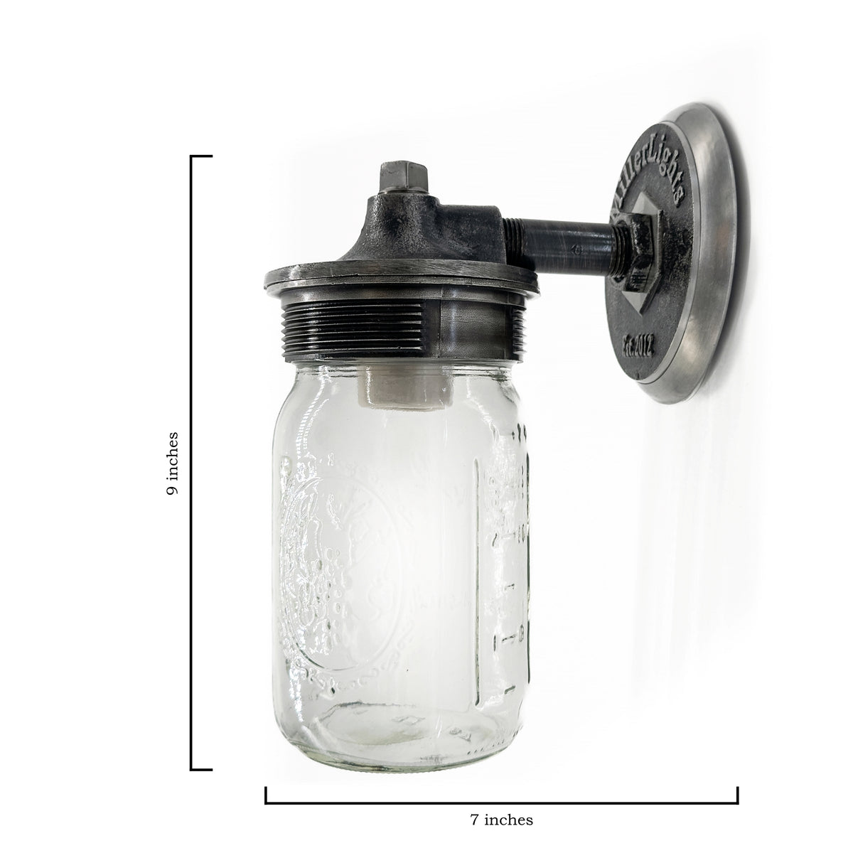 This is a mason jar wall light. The fixture is mounted on a round steel backplate that has a rugged, cast-metal look. The plate is stamped with “MillerLights – Est. 2012”, giving it a handcrafted, branded touch.