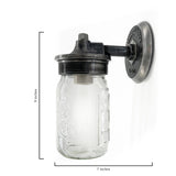 This is a mason jar wall light. The fixture is mounted on a round steel backplate that has a rugged, cast-metal look. The plate is stamped with “MillerLights – Est. 2012”, giving it a handcrafted, branded touch.