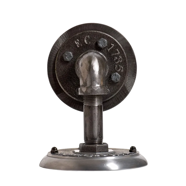 Close-up product top view of The Ward industrial wall sconce mounting plate assembly, showing the heavy-duty round iron flange with exposed structural bolts and raw black iron pipe pipe nipple joints.