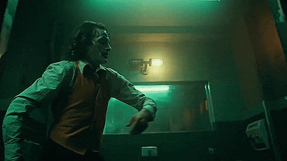 Cinematic shot from the Joker 2019 movie bathroom dance scene featuring Arthur Fleck, with the MillerLights industrial double cage vanity light fixture mounted centrally above the mirror.