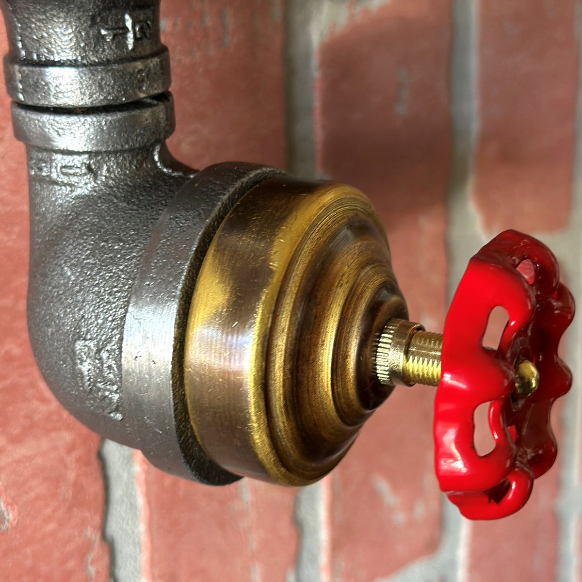Close-up of a hand turning the red metal faucet knob on a steampunk rotary light switch.