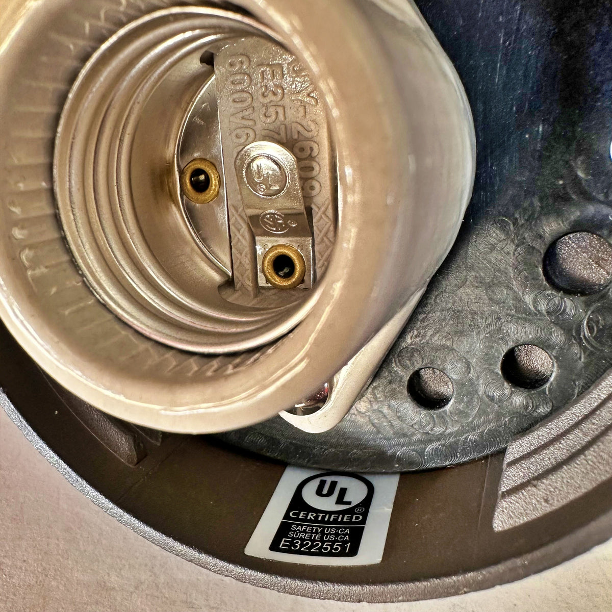 Close-up interior detail of MillerLights 'The Ward' wall sconce showing the durable porcelain E26 medium base socket alongside an official UL Certified safety compliance label for US and Canada.